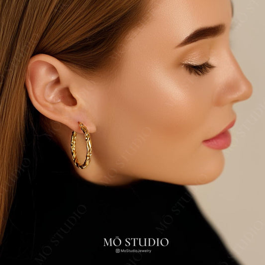 model wearing braided gold statement hoop earrings