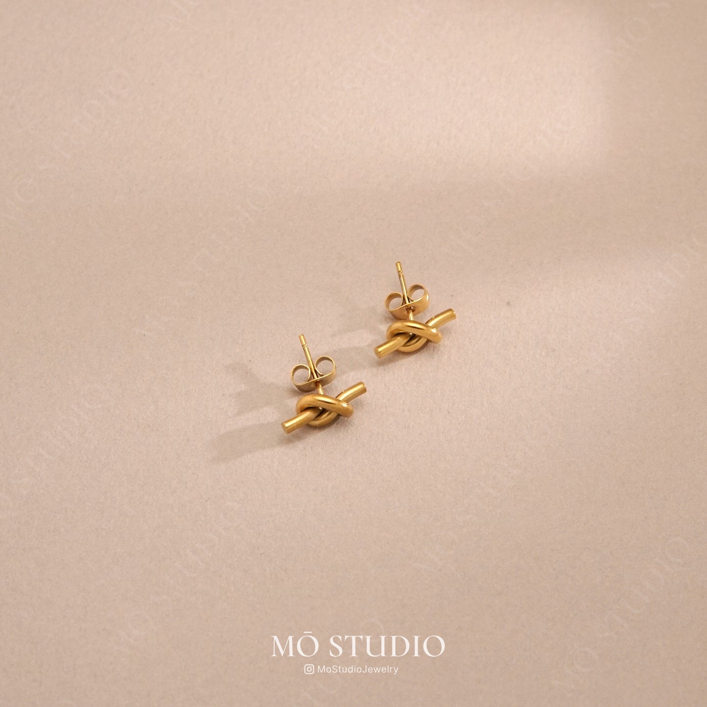 small gold knot hoop earrings on background