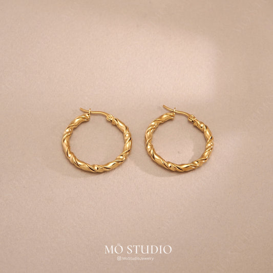chunky gold twisted rope hoop earrings on clean background