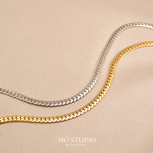 layered snake chain necklace with curb and Cuban links in gold and silver